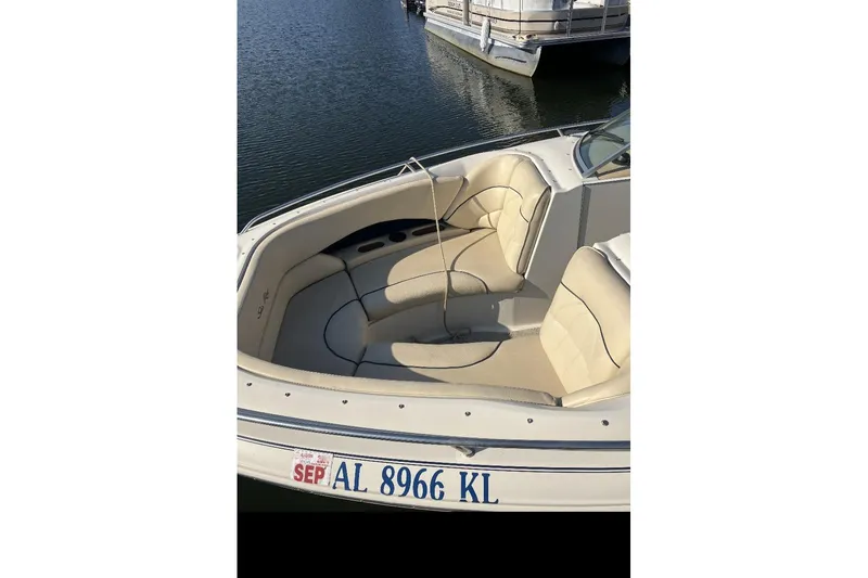 Slide: The Image of 2000 Sea Ray 230 Signature boat with beige seating, docked on calm water. - 8