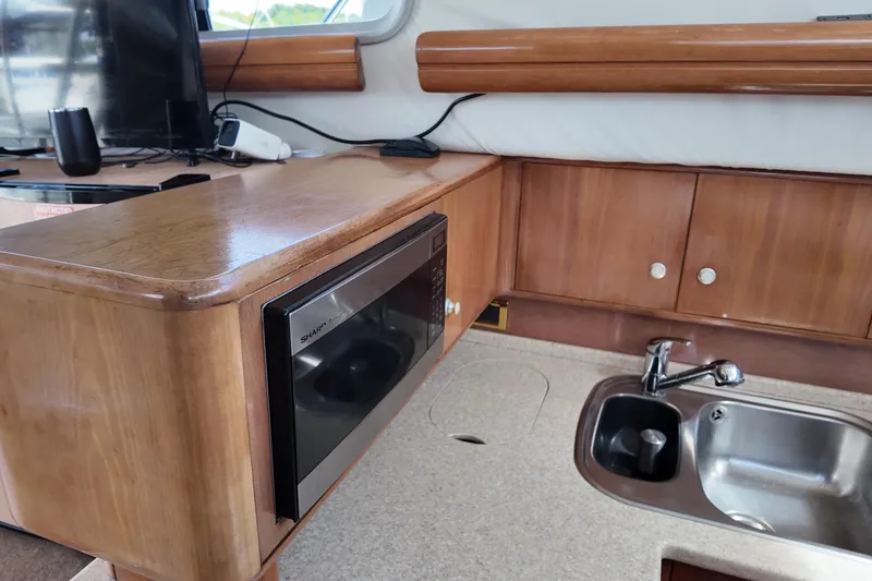 Slide: The Image of 2007 Cranchi Atlantique 40 yacht kitchen with microwave, sink, and wooden cabinetry. - 20