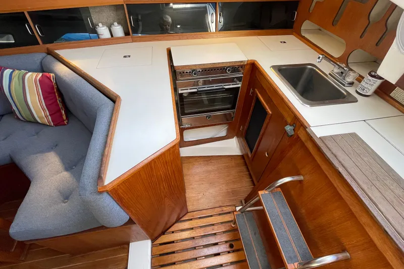 Slide: The Image of Interior of 1987 Beneteau 31 sailboat with kitchen, seating, and wooden cabinetry. - 13