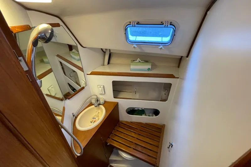 Slide: The Image of 1987 Beneteau 31 yacht bathroom with sink, mirror, and wooden accents. - 16