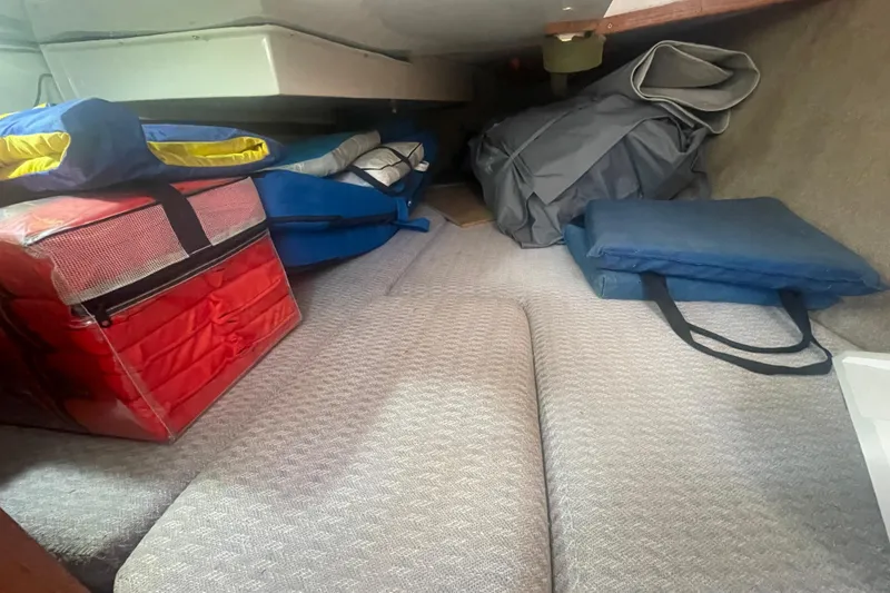 Slide: The Image of Interior storage area of a 1987 Beneteau 31 sailboat with various bags and cushions. - 17