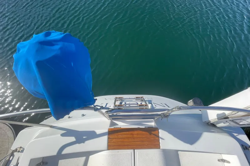 Slide: The Image of 1987 Beneteau 31 sailboat stern view with blue cover, docked on calm water. - 4