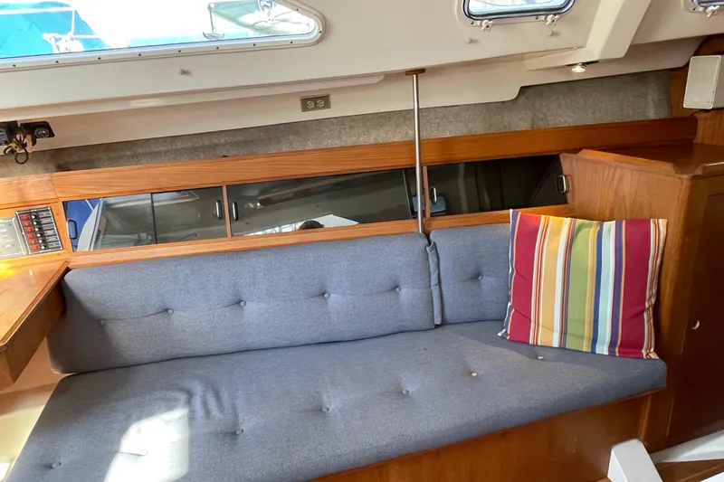 Slide: The Image of Interior of a 1987 Beneteau 31 sailboat with blue cushioned seating and striped pillow. - 9
