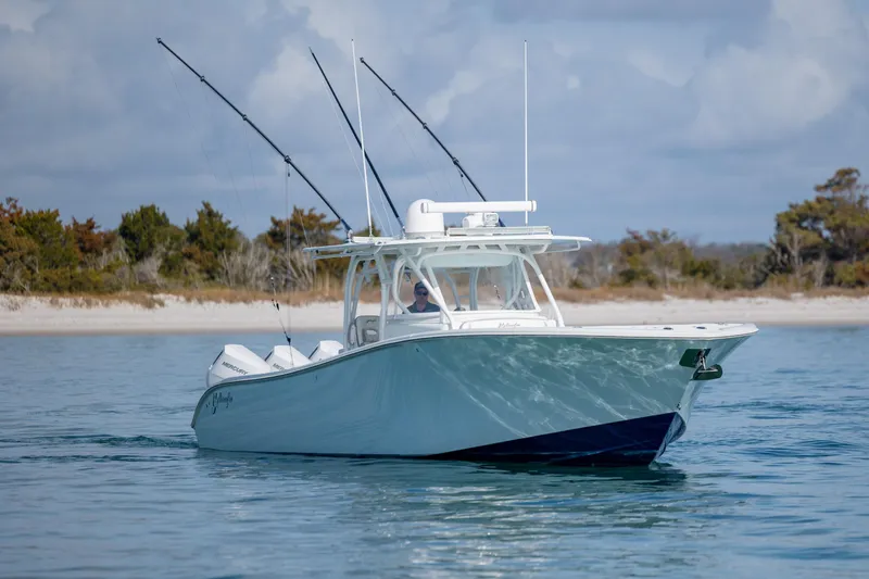 Slide: The Image of 2014 Yellowfin 42 Offshore boat cruising near a sandy shoreline with fishing rods. - 11