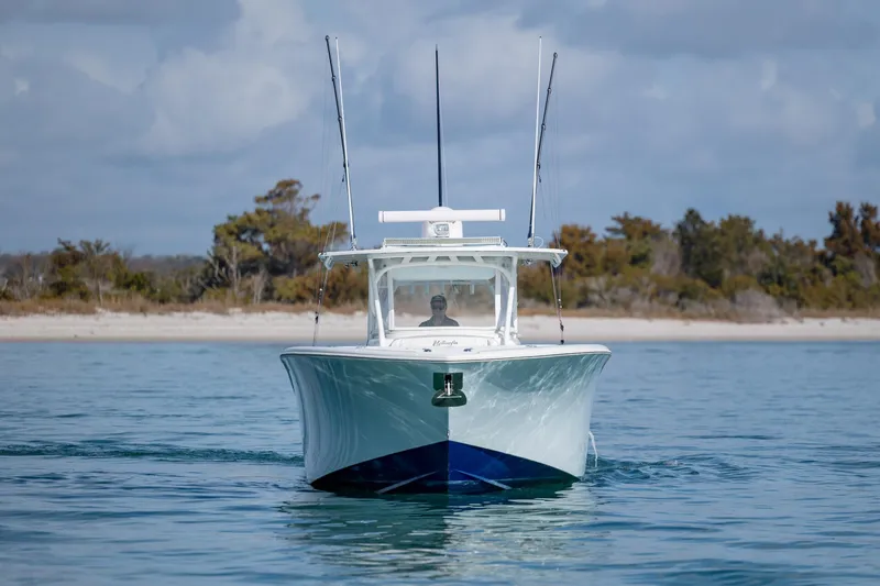 Slide: The Image of 2014 Yellowfin 42 Offshore boat cruising on calm water near a sandy shoreline. - 12