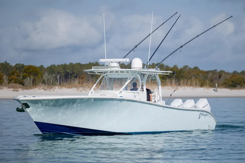 Slide: The Image of 2014 Yellowfin 42 Offshore boat cruising on calm waters near a sandy shoreline. - 2
