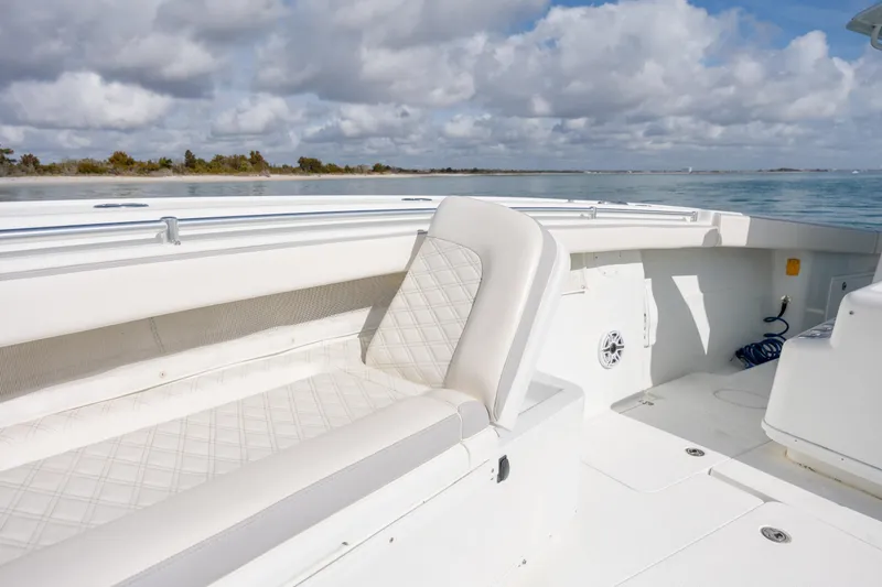 Slide: The Image of 2014 Yellowfin 42 Offshore boat interior with white seating, on calm water under cloudy sky. - 34