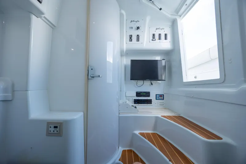 Slide: The Image of 2014 Yellowfin 42 Offshore interior with control panels, TV, and wooden steps. - 39