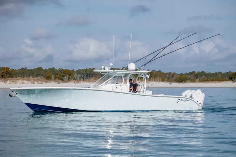 Slide: The Image of 2014 Yellowfin 42 Offshore boat cruising near a sandy shoreline. - 5