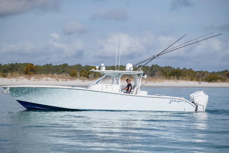 Slide: The Image of 2014 Yellowfin 42 Offshore boat cruising on calm waters near a sandy shoreline. - 6