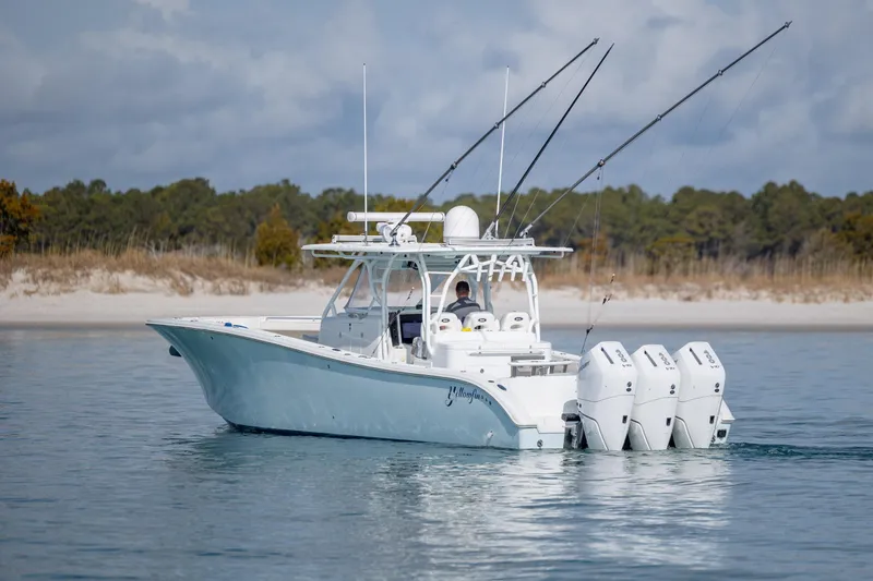 Slide: The Image of 2014 Yellowfin 42 Offshore boat with triple engines on calm water near a sandy shore. - 7