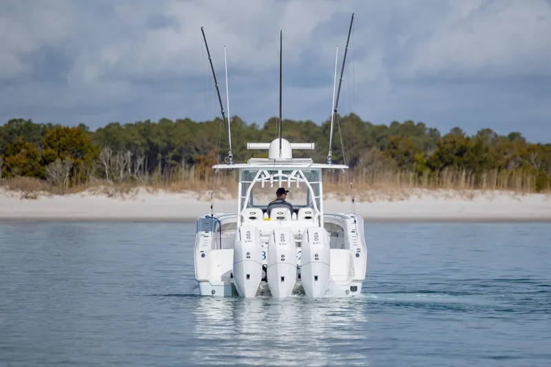 Slide: The Image of 2014 Yellowfin 42 Offshore boat with four engines, cruising near a sandy shoreline. - 8