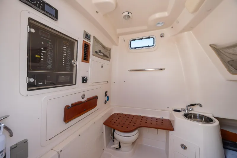 Slide: The Image of Interior of 2013 Grady-White Canyon 306 boat, featuring a compact bathroom with sink and control panel. - 12