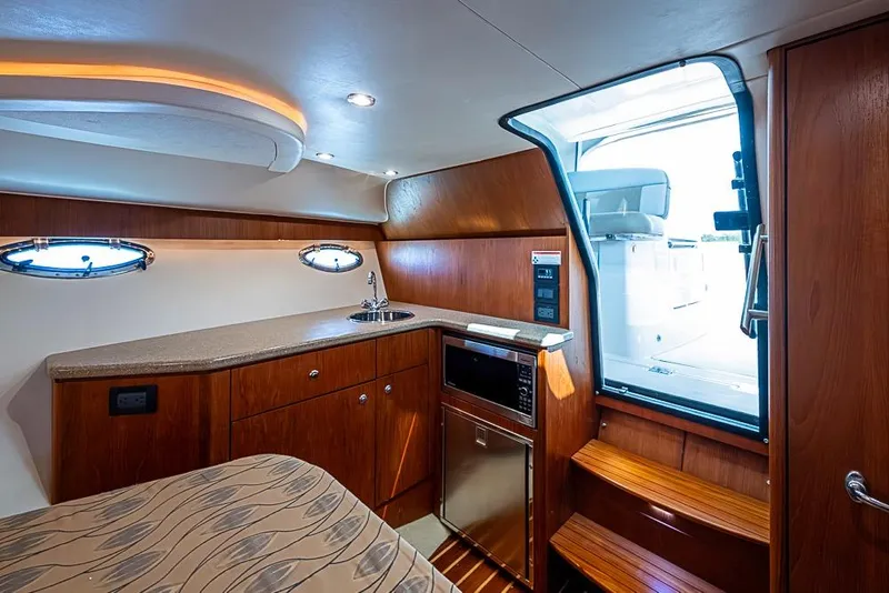 Slide: The Image of Interior of 2012 Tiara Yachts 3100 Coronet, featuring kitchenette and wooden cabinetry. - 26