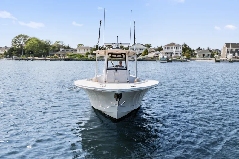 Slide: The Image of 2024 Regulator 34 boat on calm water near residential shoreline. - 2