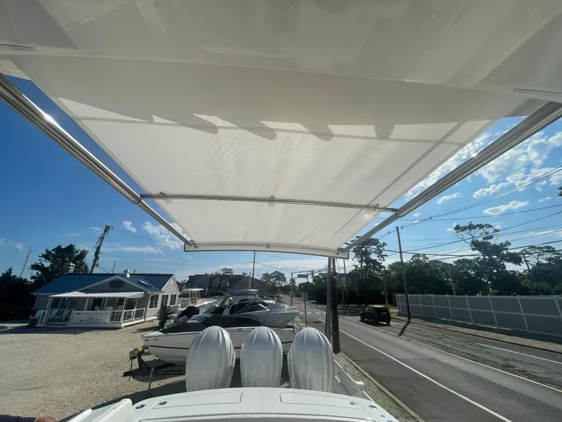 Slide: The Image of 2024 Regulator 34 boat with sunshade and engines, parked outdoors. - 49