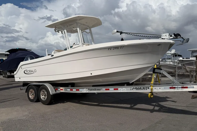 The Image of 2022 Robalo R242 Center Console boat on trailer under cloudy sky. - 0