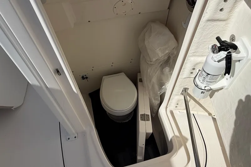 Slide: The Image of 2022 Robalo R242 Center Console boat interior with toilet and fire extinguisher. - 12