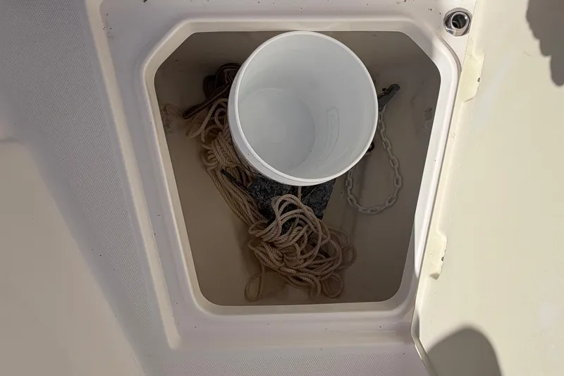 Slide: The Image of Storage compartment on 2022 Robalo R242 Center Console with rope, chain, and bucket. - 15