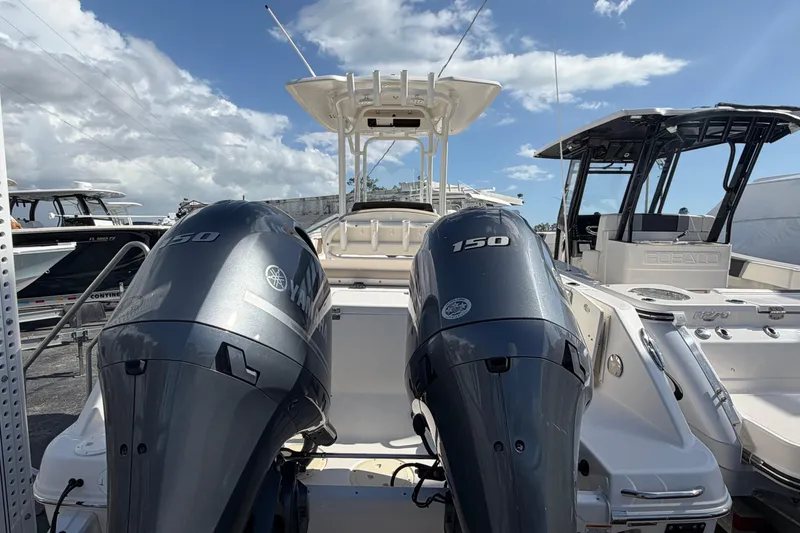Slide: The Image of 2022 Robalo R242 Center Console boat with dual Yamaha 150 engines, docked under a clear sky. - 2