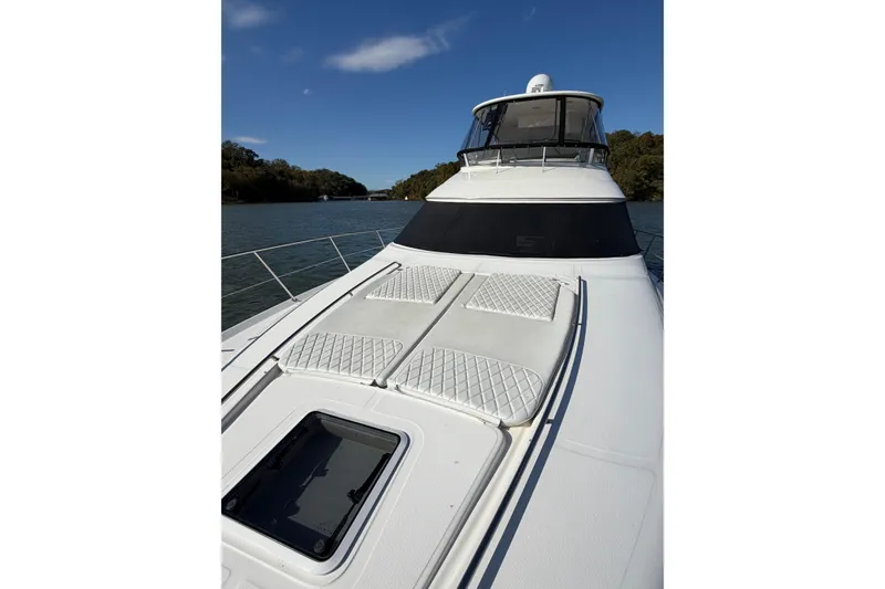 Slide: The Image of 2003 Sea Ray 560 Sedan Bridge yacht on calm water, featuring sun pads and sleek design. - 13