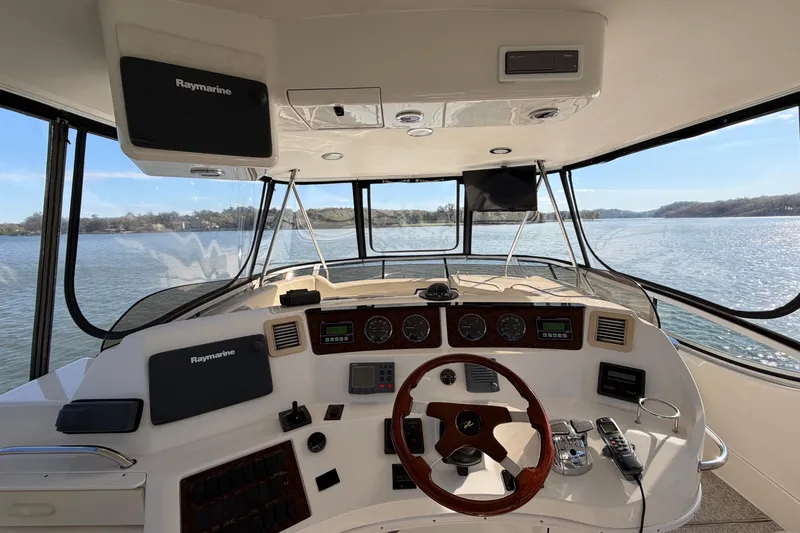 Slide: The Image of 2003 Sea Ray 560 Sedan Bridge helm with Raymarine electronics, overlooking serene waters. - 16
