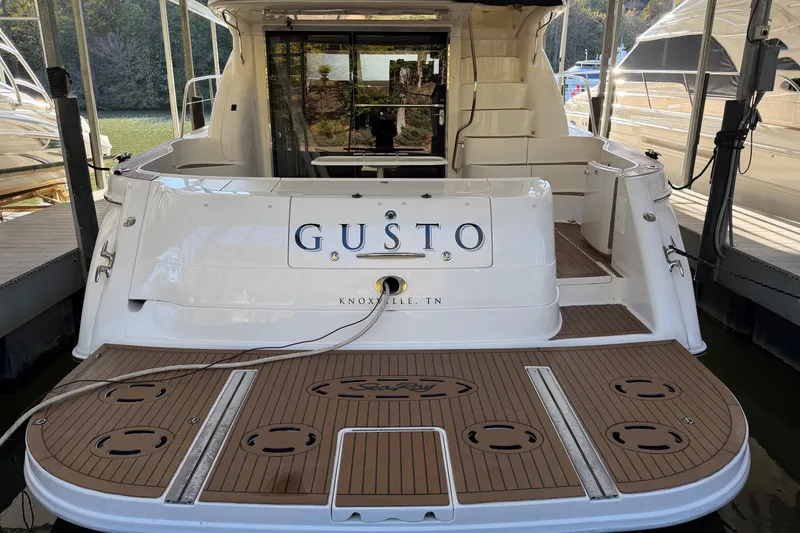Slide: The Image of 2003 Sea Ray 560 Sedan Bridge yacht docked, rear view with "Gusto" nameplate. - 20