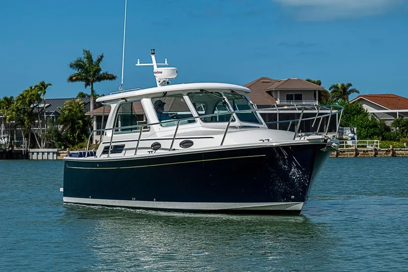 The Image of 2011 Back Cove 30 boat cruising on a sunny day near waterfront homes. - 0
