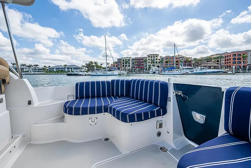 Slide: The Image of 2011 Back Cove 30 boat with striped seating, marina view, colorful buildings in background. - 14