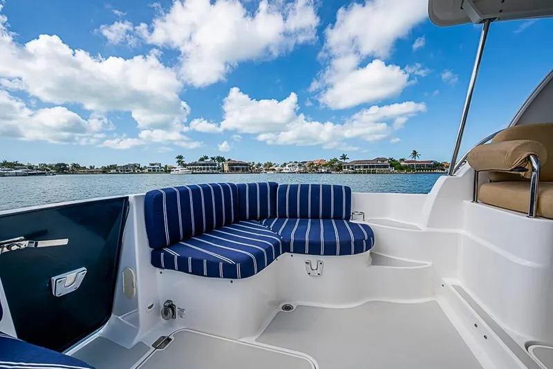 Slide: The Image of 2011 Back Cove 30 boat with striped seating, scenic waterfront view. - 15