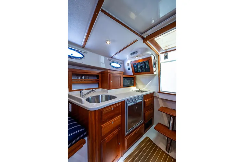 Slide: The Image of 2011 Back Cove 30 yacht interior with modern kitchen, wood cabinetry, and stainless steel sink. - 17