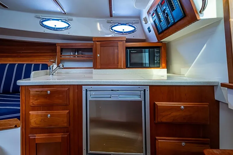 Slide: The Image of 2011 Back Cove 30 yacht interior with kitchenette, featuring wood cabinetry and modern appliances. - 19
