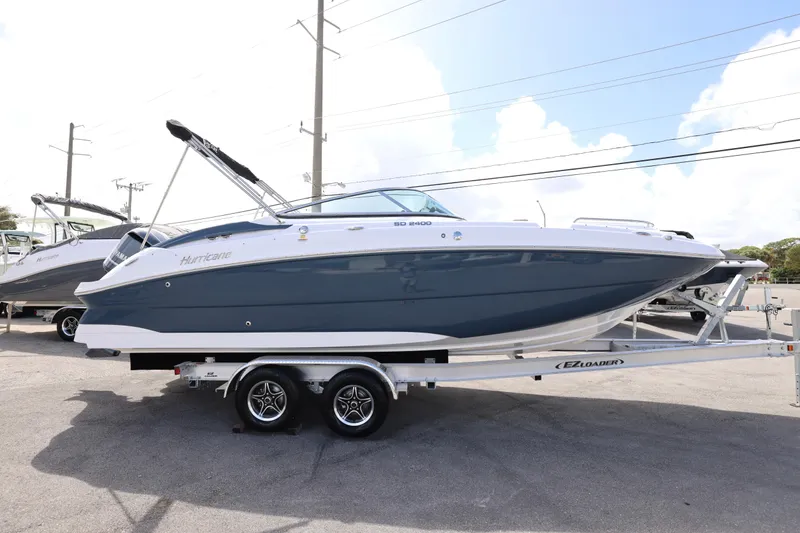 Slide: The Image of 2026 Hurricane SunDeck 2400 OB boat on trailer, parked outdoors. - 25