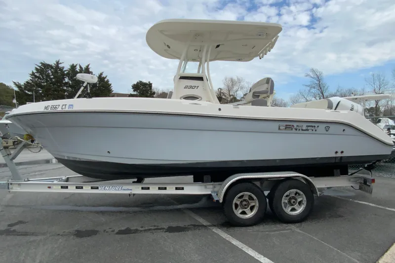 Slide: The Image of 2019 Century 2301 Center Console boat on trailer, parked outdoors under cloudy sky. - 6