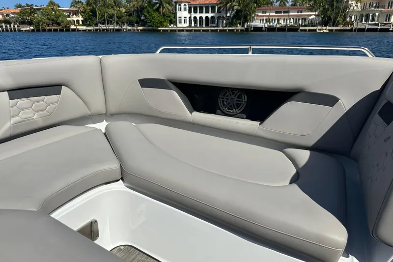 Slide: The Image of 2022 Four Winns HD8 OB boat interior with gray seating, near waterfront homes. - 13