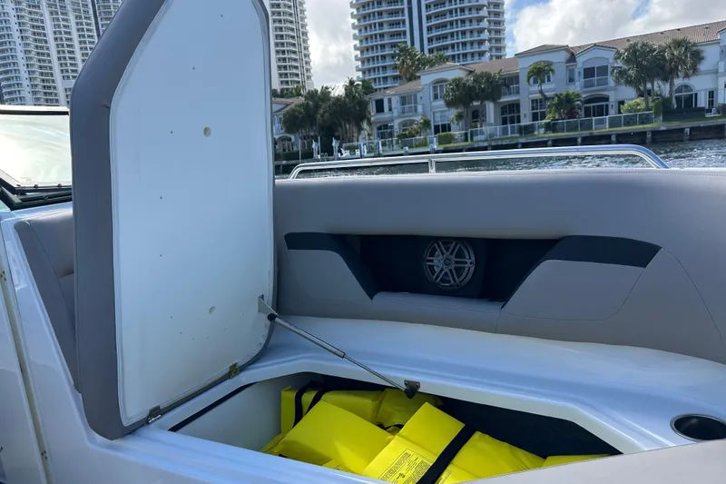 Slide: The Image of 2022 Four Winns HD8 OB boat storage compartment with life jackets, waterfront view. - 14