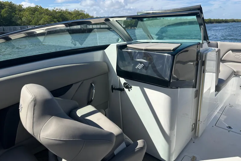 Slide: The Image of 2022 Four Winns HD8 OB boat interior with seating and console, on a sunny day by the water. - 24