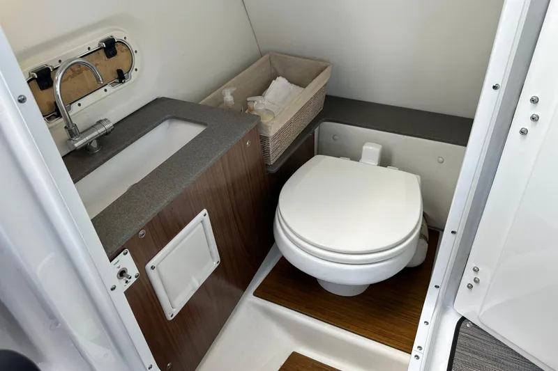Slide: The Image of 2022 Four Winns HD8 OB boat bathroom with sink, toilet, and storage basket. - 25