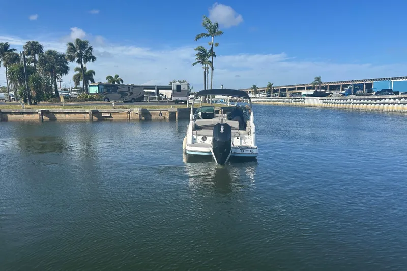 Slide: The Image of 2022 Four Winns HD8 OB boat on calm water, with palm trees and blue sky. - 3