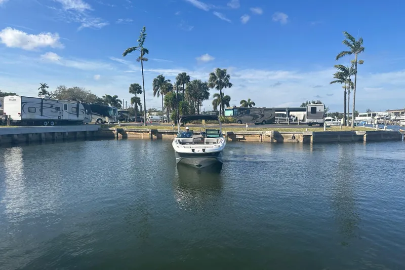 Slide: The Image of 2022 Four Winns HD8 OB boat on calm water near RV park and palm trees. - 4