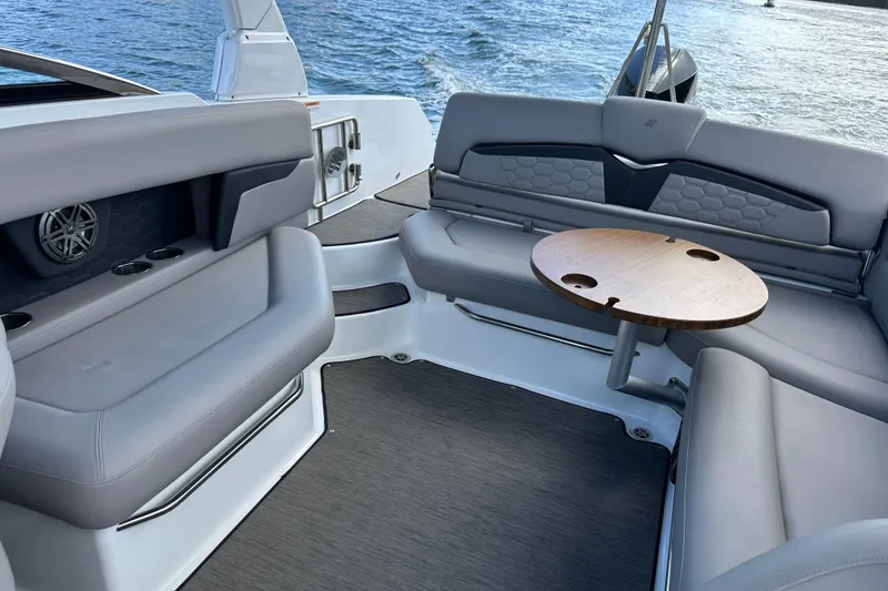 Slide: The Image of 2022 Four Winns HD8 OB boat interior with gray seating and wooden table. - 45