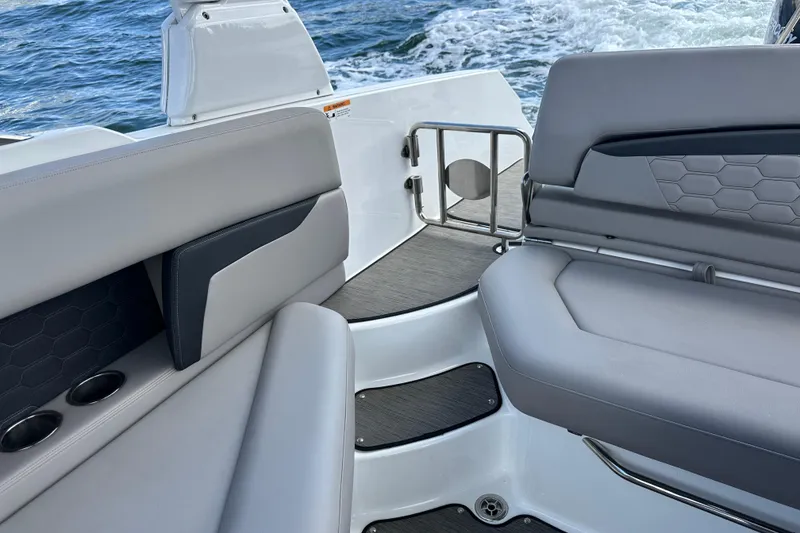 Slide: The Image of 2022 Four Winns HD8 OB boat interior with gray seating and cup holders on the water. - 48