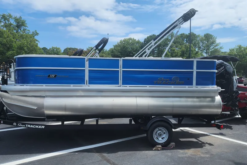 The Image of 2026 Sun Tracker Party Barge 18 DLX pontoon boat on trailer in parking lot. - 0