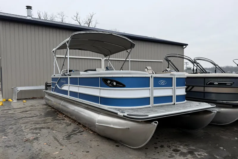 The Image of 2026 Bentley Pontoons Legacy 240 Navigator Ext, blue and silver, docked near a building. - 1