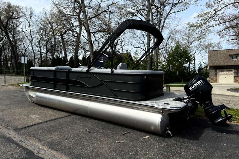 Slide: The Image of 2026 Bentley Pontoons Legacy 220 Cruise XL pontoon boat with Suzuki outboard motor on a driveway. - 3