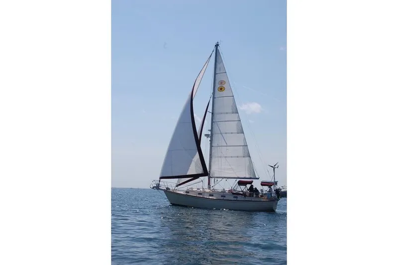 Slide: The Image of 1995 Island Packet 37 sailboat cruising on calm waters under clear skies. - 11
