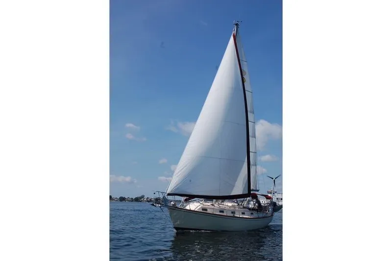 Slide: The Image of 1995 Island Packet 37 sailboat on calm water under clear blue sky. - 12