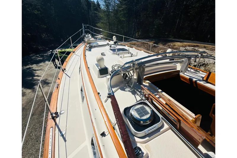 Slide: The Image of 1995 Island Packet 37 sailboat cockpit with wooden accents, surrounded by trees. - 17