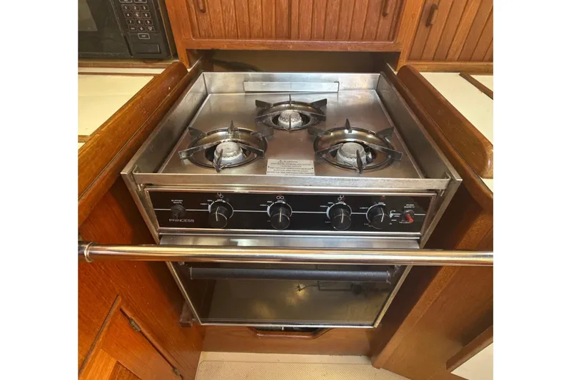 Slide: The Image of 1995 Island Packet 37 yacht interior kitchen with stove, sink, and wooden cabinetry. - 37