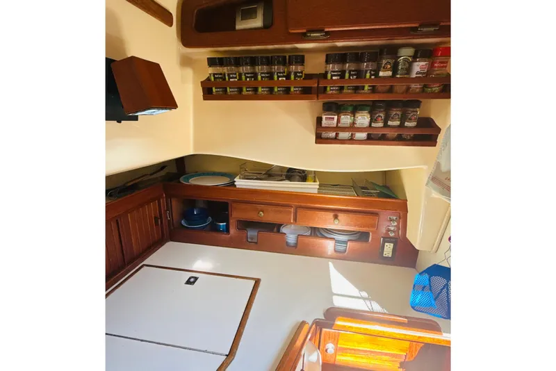 Slide: The Image of Cozy 1995 Island Packet 37 yacht kitchen with wooden cabinetry and compact appliances. - 38